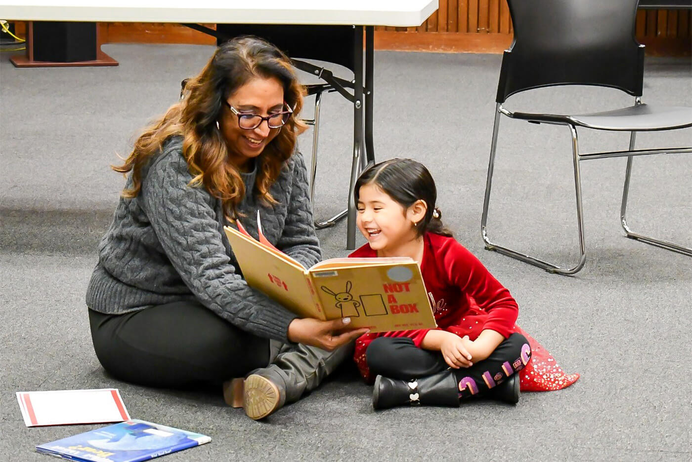 Adult Reading book to child on the floor